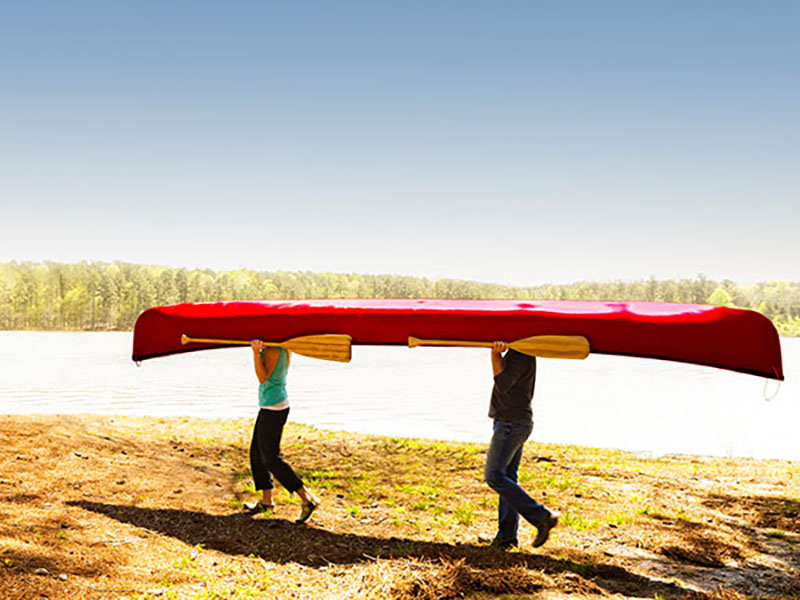 people carrying canoe at lake