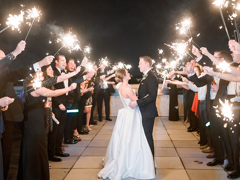 bride and groom walking passed guests with sparklers at night