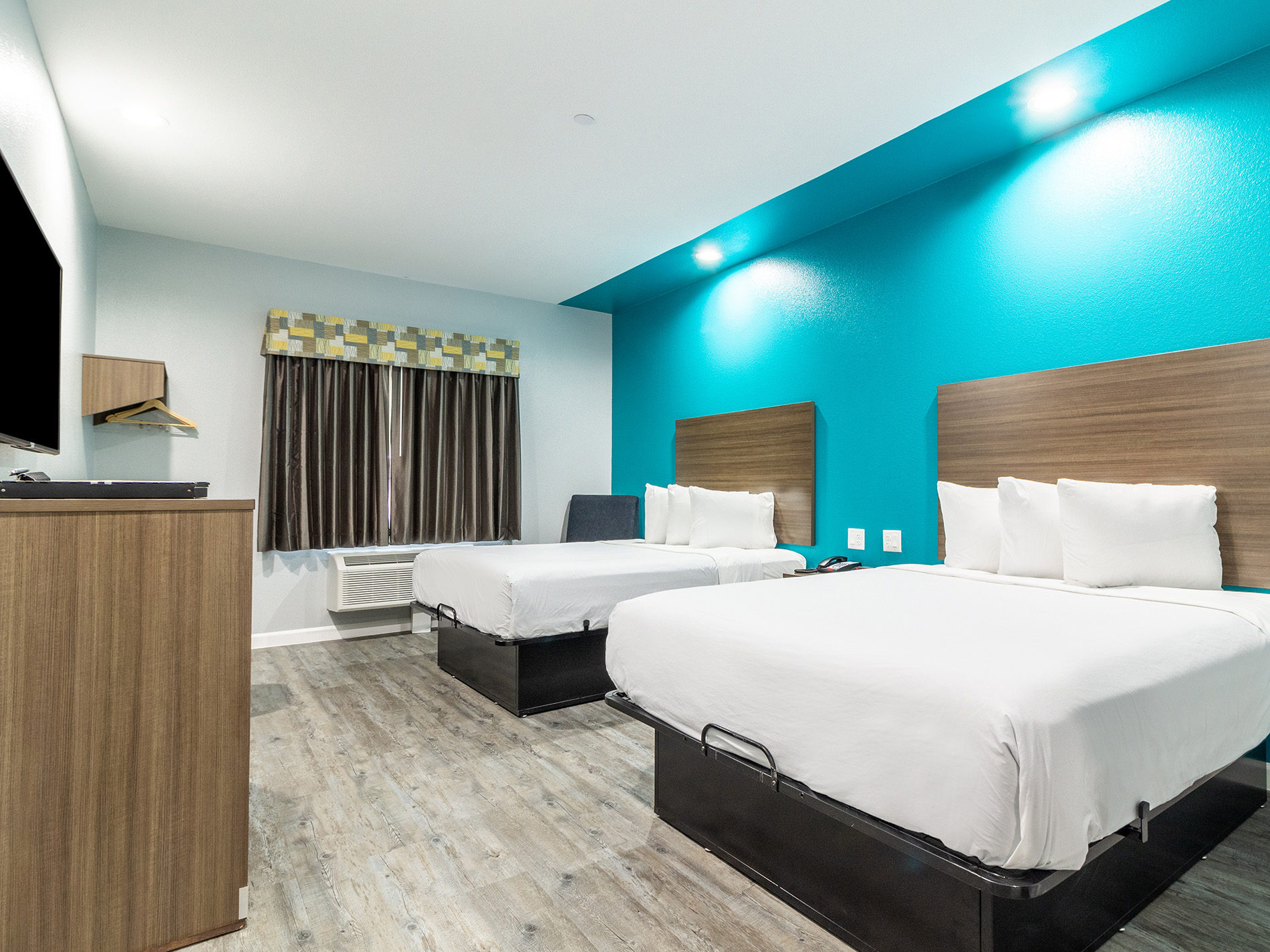abvi guest room with bright blue walls and two queen bed with white linens