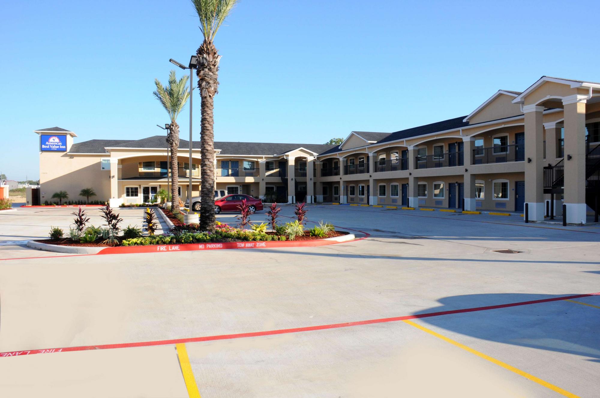 Hotel exterior with ample parking and palm trees