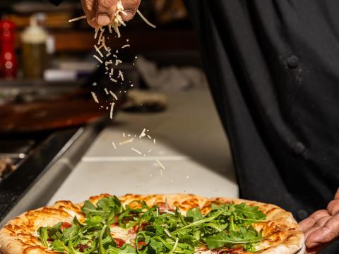 A chef adding final touches to a pizza ready to serve to customers at Certo! restaurant in Washington, D.C.